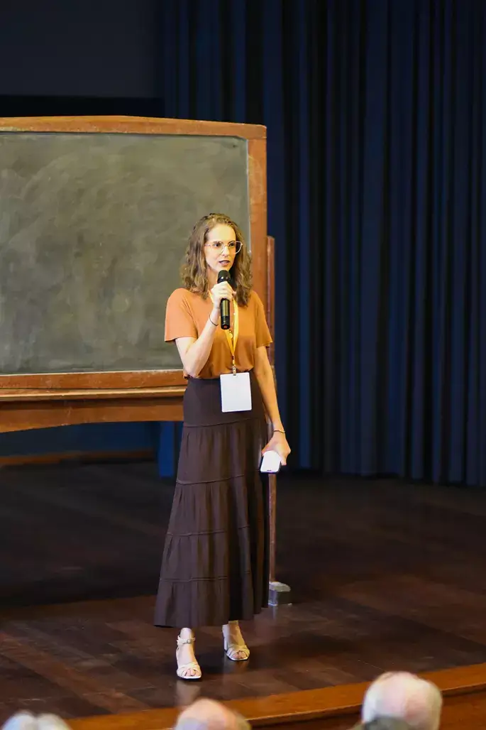 Foto de Mariana Azoubel no palco, durante congresso de saúde integrativa, falando sobre terapias complementares e antroposofia.
